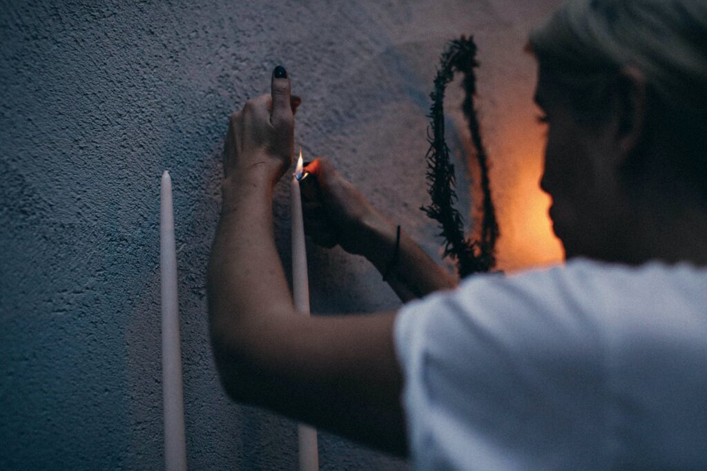 crop woman lighting candle near wall